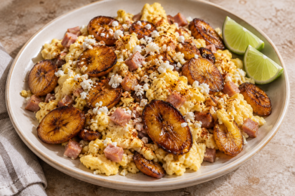 Fluffy scrambled eggs with diced ham and golden caramelized plantains, topped with crumbled cotija cheese and served with lime wedges.