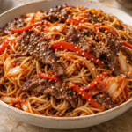 Bulgogi beef and thin noodles tossed with red bell pepper and kimchi in a glossy sauce, topped with toasted sesame seeds.